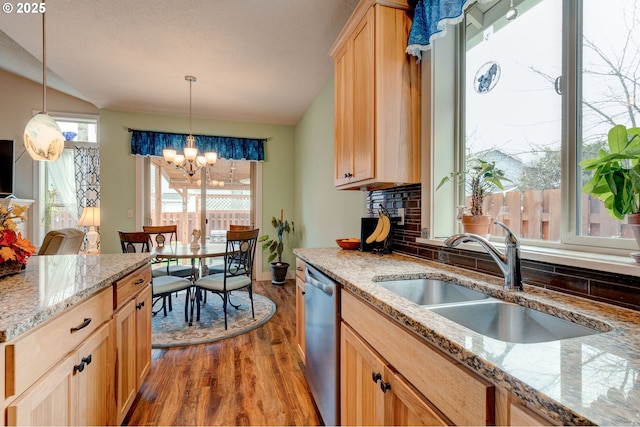 kitchen featuring light wood-style flooring, a sink, backsplash, stainless steel dishwasher, and vaulted ceiling