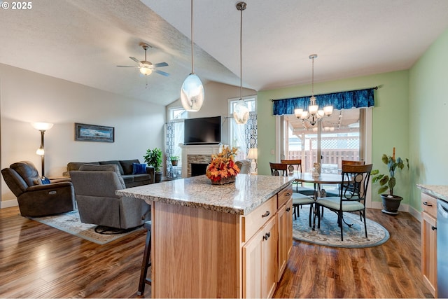 kitchen with a kitchen bar, open floor plan, a stone fireplace, and dark wood-type flooring