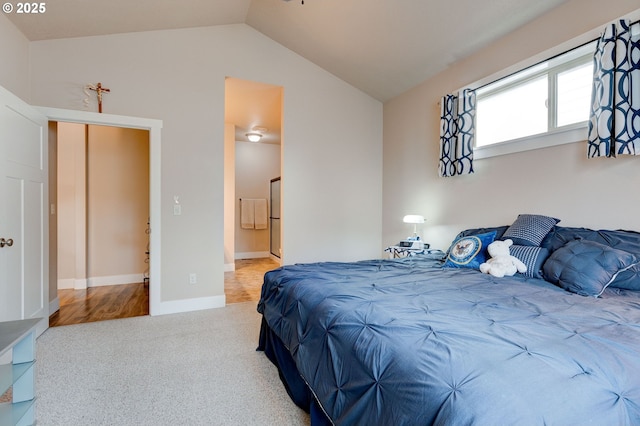 bedroom with baseboards, ensuite bath, carpet flooring, and vaulted ceiling