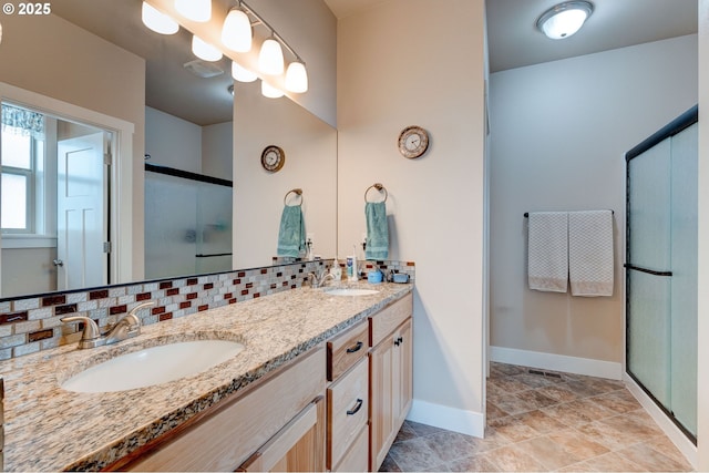 bathroom featuring a shower stall, double vanity, backsplash, and a sink