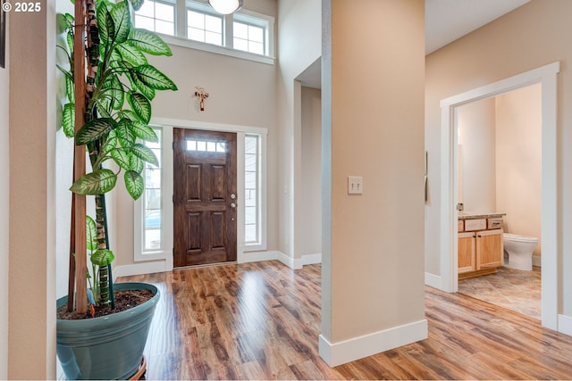 entrance foyer with light wood-type flooring, baseboards, and a high ceiling