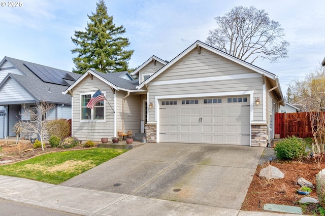 view of front of property featuring stone siding, driveway, a garage, and fence