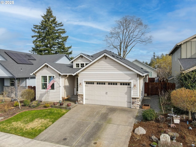 view of front of home with fence, concrete driveway, roof with shingles, stone siding, and an attached garage