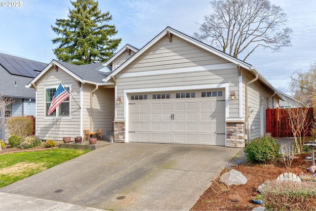 view of front of home featuring stone siding, driveway, a garage, and fence