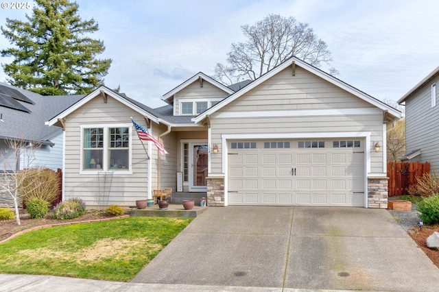 view of front of home featuring stone siding, concrete driveway, an attached garage, and fence