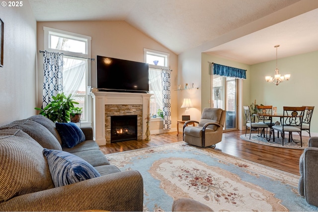 living area with wood finished floors, baseboards, an inviting chandelier, a fireplace, and vaulted ceiling