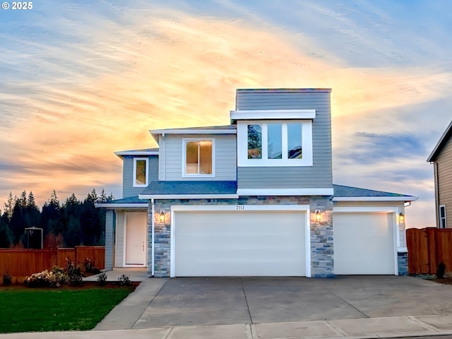 view of front of home featuring a garage, stone siding, driveway, and fence