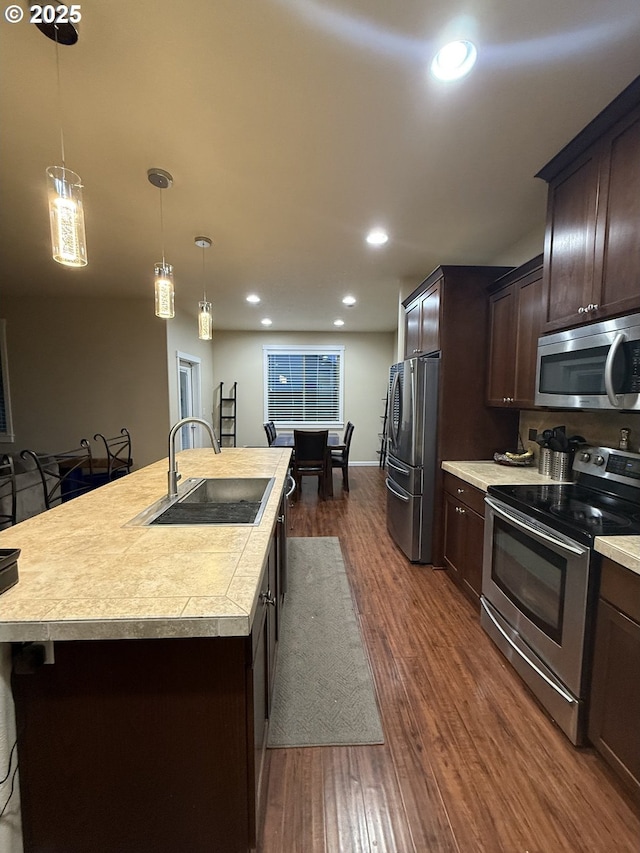 4002 N 3rd Cir, Ridgefield, WA 98642 - kitchen featuring appliances with stainless steel finishes, light countertops, a sink, dark brown cabinets, and dark wood finished floors