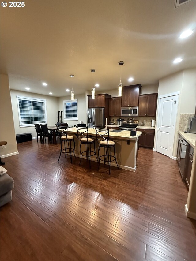 4002 N 3rd Cir, Ridgefield, WA 98642 - kitchen featuring appliances with stainless steel finishes, dark brown cabinets, a kitchen breakfast bar, recessed lighting, and light countertops