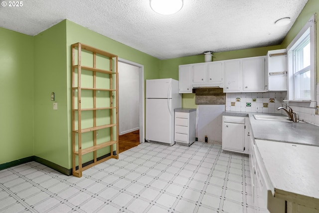 10303 SE Bull Run Rd, Corbett, OR 97019 - kitchen with freestanding refrigerator, a sink, light floors, white cabinetry, and a textured ceiling