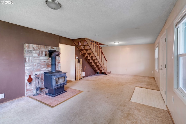 10303 SE Bull Run Rd, Corbett, OR 97019 - unfurnished living room with carpet, a wood stove, stairway, a textured ceiling, and plenty of natural light