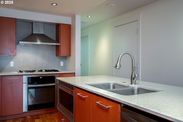 kitchen with stainless steel appliances, dark hardwood / wood-style floors, tasteful backsplash, wall chimney exhaust hood, and sink