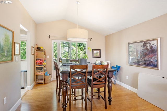 dining room with baseboards, light wood-style flooring, and lofted ceiling