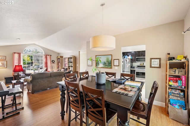 dining space with vaulted ceiling and wood finished floors
