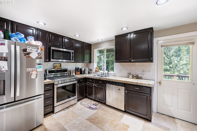 kitchen with light countertops, appliances with stainless steel finishes, tasteful backsplash, and a sink