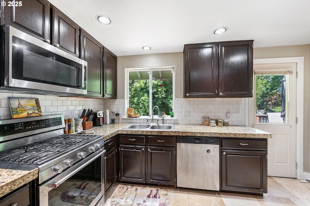 kitchen featuring stainless steel appliances, decorative backsplash, a sink, and plenty of natural light