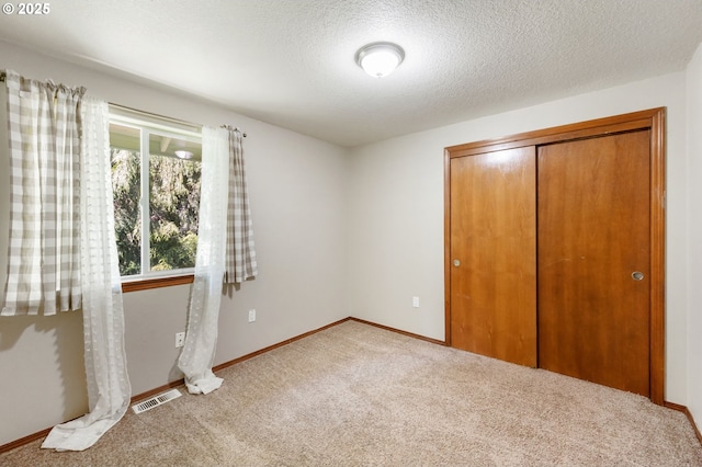 unfurnished bedroom featuring carpet, a closet, baseboards, and visible vents