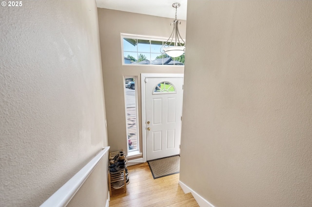entrance foyer with baseboards, light wood finished floors, and a textured wall