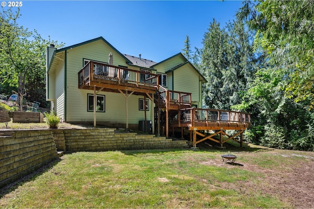back of property with a chimney, a wooden deck, a fire pit, and a lawn