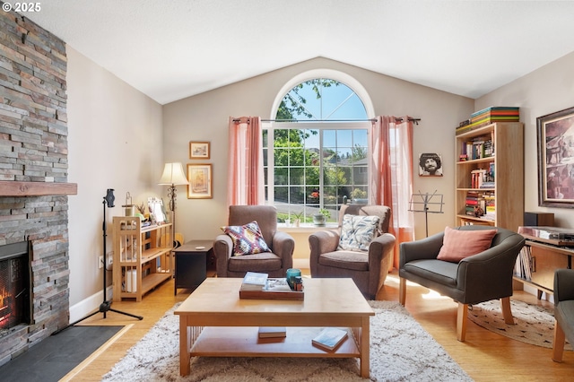 sitting room with vaulted ceiling, light wood-style flooring, and a stone fireplace