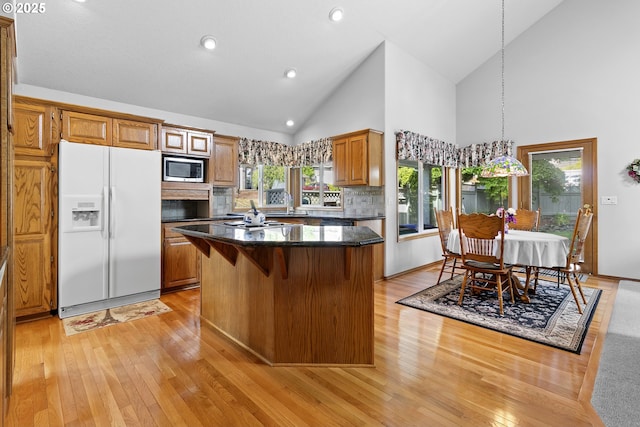 8346 SE 141st Ave, Portland, OR 97236 - kitchen featuring white refrigerator with ice dispenser, stainless steel microwave, a center island, light wood finished floors, and high vaulted ceiling
