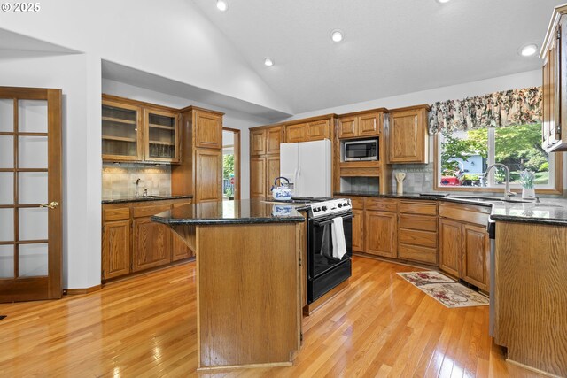 8346 SE 141st Ave, Portland, OR 97236 - kitchen with black gas range oven, white refrigerator with ice dispenser, stainless steel microwave, a kitchen island, and lofted ceiling