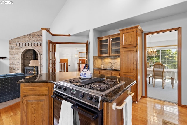 8346 SE 141st Ave, Portland, OR 97236 - kitchen featuring range with electric cooktop, a wood stove, a chandelier, brown cabinetry, and light wood finished floors
