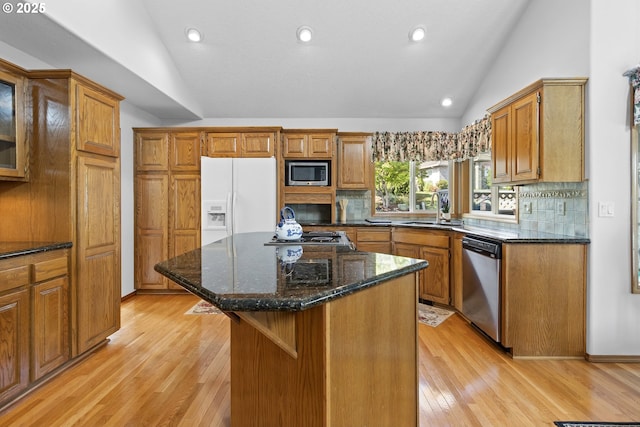 8346 SE 141st Ave, Portland, OR 97236 - kitchen featuring stainless steel appliances, vaulted ceiling, brown cabinets, light wood-style flooring, and decorative backsplash