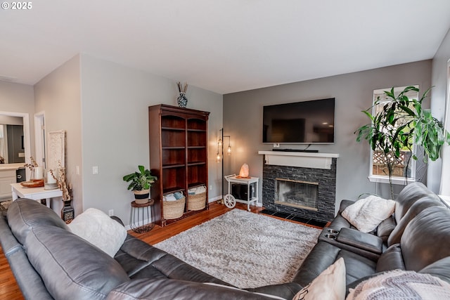 living area with wood finished floors, a fireplace, and baseboards