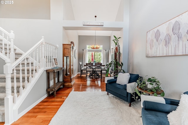 entryway with stairs, wood finished floors, a towering ceiling, and baseboards