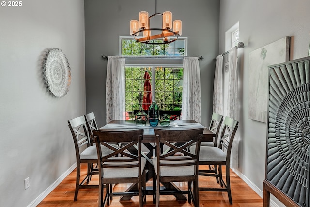 dining area with wood finished floors, a chandelier, and baseboards