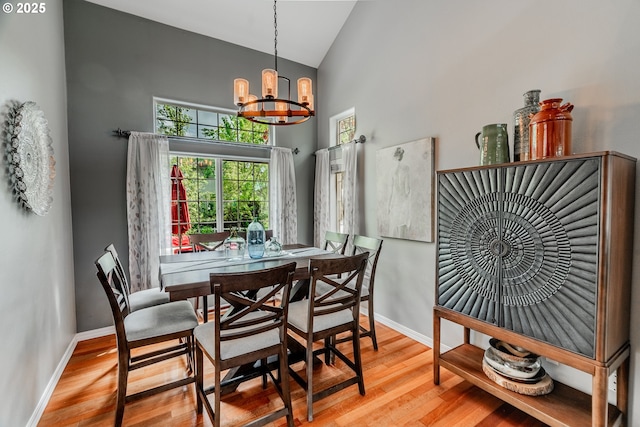 dining space with a chandelier, high vaulted ceiling, baseboards, and wood finished floors