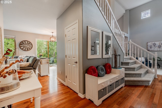 foyer with light wood-style flooring, stairs, baseboards, and a towering ceiling