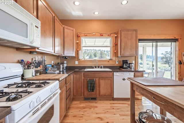 kitchen featuring recessed lighting, a sink, light wood-style floors, visible vents, and white appliances
