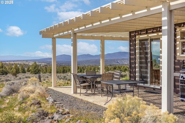 view of patio / terrace featuring outdoor dining space, a pergola, and a mountain view