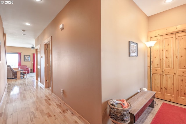 hall featuring baseboards, recessed lighting, and light wood finished floors