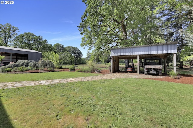 view of yard featuring an outbuilding, a detached carport, and driveway
