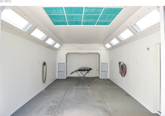unfurnished room featuring lofted ceiling, concrete floors, and baseboards