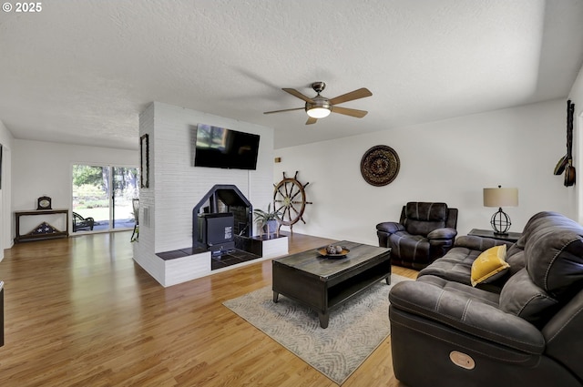 living area featuring a ceiling fan, light wood-type flooring, and a textured ceiling