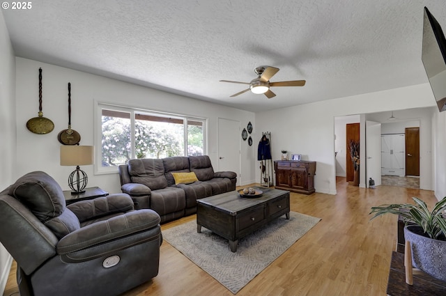 living area with ceiling fan, light wood-style flooring, and a textured ceiling