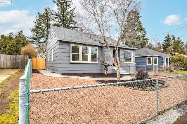 bungalow-style house featuring a shingled roof and a fenced front yard