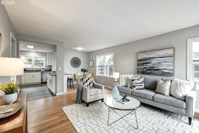 living area featuring light wood-style floors, plenty of natural light, and baseboards