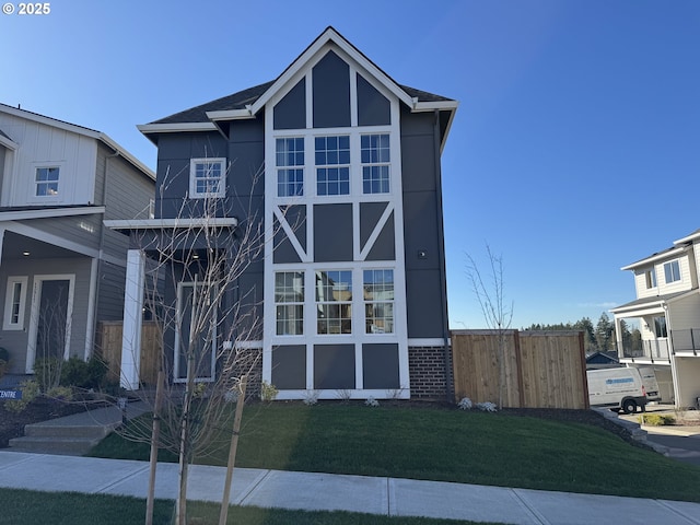 view of front of home with brick siding, a front yard, and fence