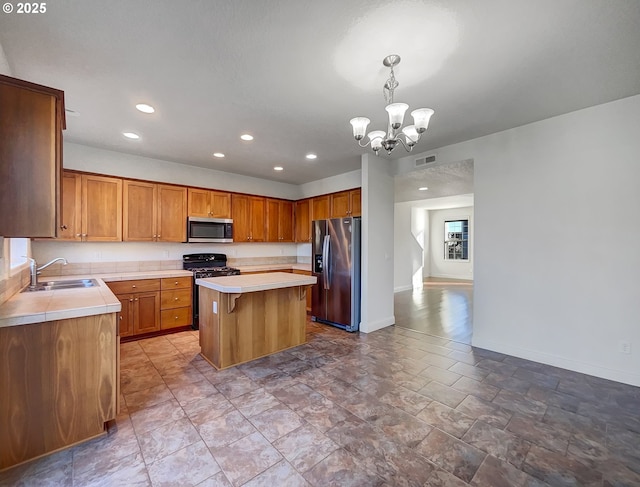 kitchen featuring visible vents, a kitchen island, an inviting chandelier, a sink, and stainless steel appliances