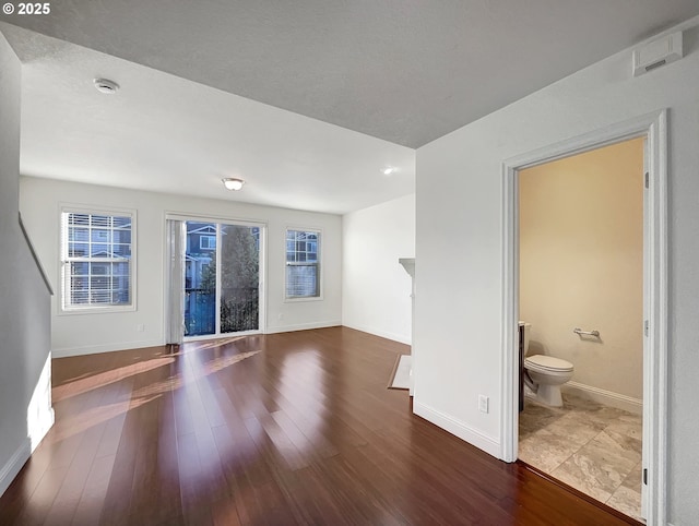 unfurnished living room with a wealth of natural light, baseboards, and wood finished floors