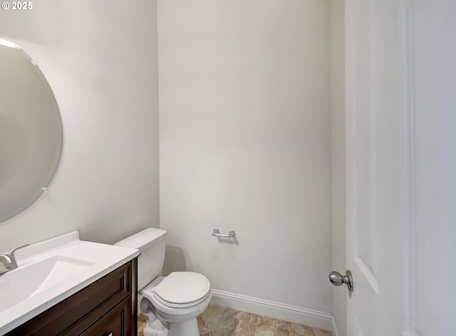 half bathroom featuring toilet, vanity, and baseboards