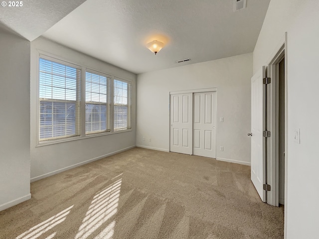 unfurnished bedroom with visible vents, carpet floors, and baseboards