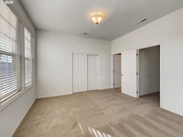 unfurnished bedroom featuring carpet flooring, baseboards, visible vents, and a closet