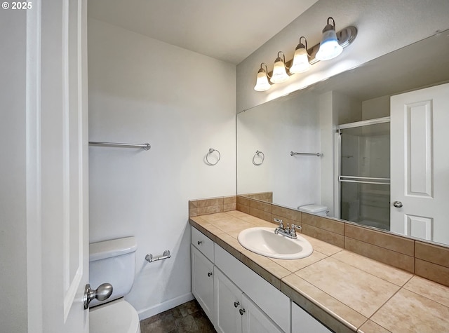 bathroom featuring an enclosed shower, toilet, vanity, and baseboards