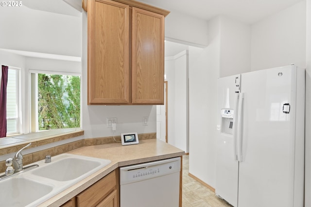 kitchen with a sink, white appliances, and light countertops
